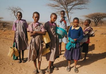 group of young people searching for water against a dusty backdrop in Kenya
