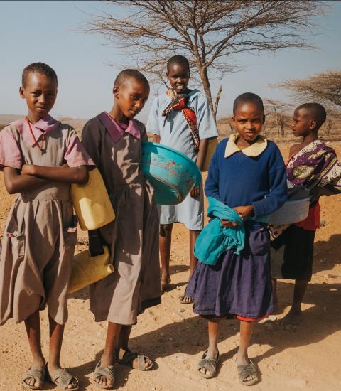 group of young people searching for water against a dusty backdrop in Kenya